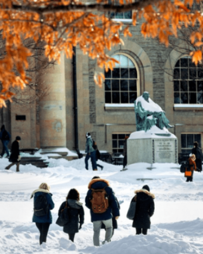 Students walking in the snow in front of Goldwin Smith Hall and the AD White Statue